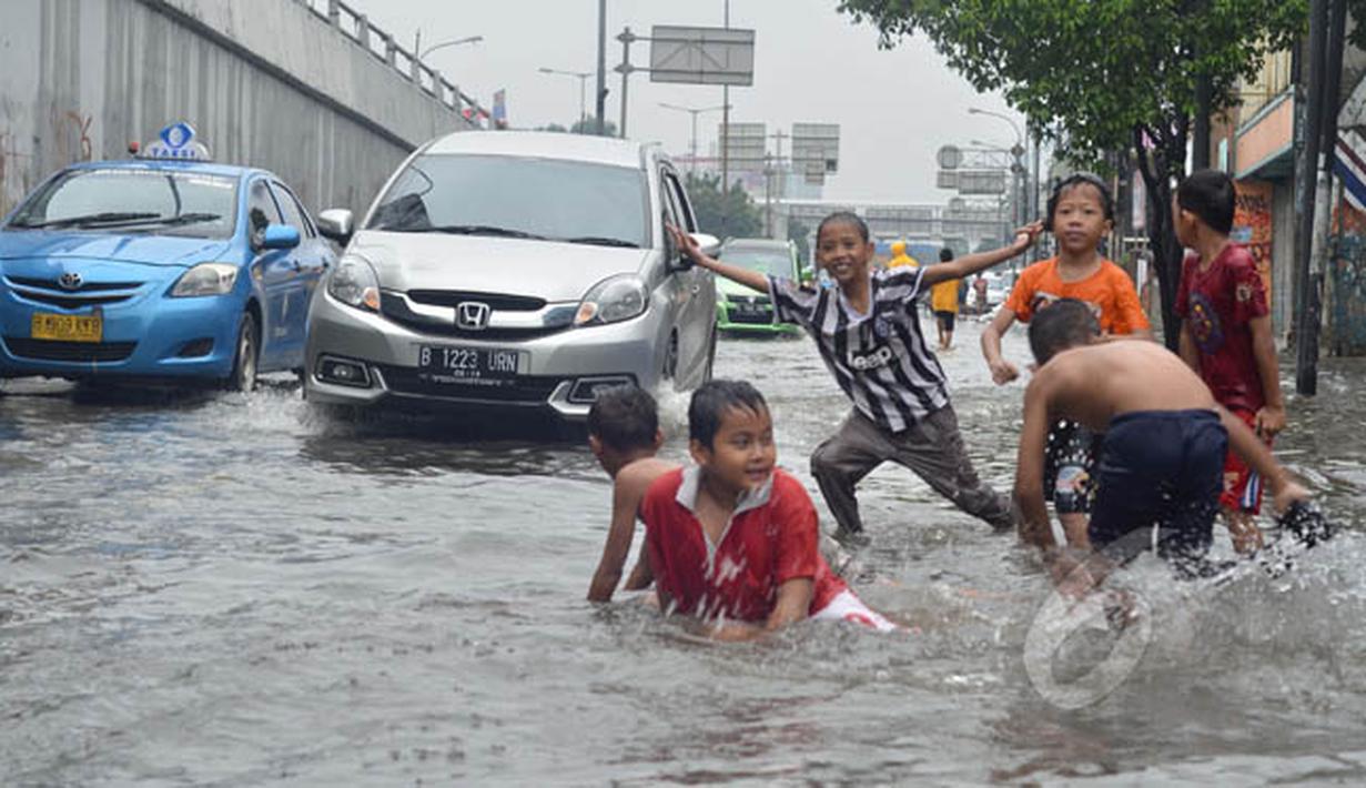 Anak-anak asyik bermain genangan air di Jalan Pramuka, Jakarta, Minggu (1/2/2015). (Liputan6.com/Andrian M Tunay)
