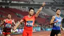Pelari China, Su Bingtian (tengah) mengacungkan tangannya seusai menjadi yang tercepat dalam final lari 100m putra Asian Games ke-18 di Stadion Utama Gelora Bung Karno, Jakarta, Minggu (26/8). (ANTARA FOTO/ INASGOC/ Jessica Margaretha/mes/18)