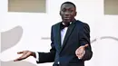 Khaby Lame berpose dengan ciri khasnya saat tiba untuk pemutaran film "Il Signore Delle Formiche" (Penguasa Semut) selama Venice Film Festival 2022 ke-79 di Lido di Venesia, Italia (6/9/2022). YouTuber Italia kelahiran Senegal ini tampil mengenakan tuxedo hitam di acara tersebut. (AFP/Tiziana Fabi)