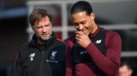 Pelatih Liverpool, Jurgen Klopp, berbincang dengan Virgil van Dijk saat sesi latihan jelang laga Liga Champions di Melwood, Liverpool, Senin (8/4). Liverpool akan berhadapna dengan Porto. (AFP/Paul Ellis)