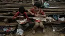 Anak-anak memakan makanan yang dibagikan di Babo, Aceh Tamiang, pada Senin 15 Desember 2025. Ancaman gangguan kesehatan menghantui anak-anak korban bencana banjir bandang dan tanah longsor yang terjadi di berbagai wilayah di Aceh, Sumatera Utara, dan Sumatera Barat. (Yasuyoshi CHIBA/AFP)