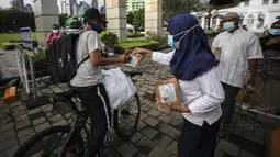 Petugas membagikan takjil kepada pesepeda secara drive thru di Kompleks Masjid Al-Azhar, Jakarta, Kamis (15/4/2021). Pengelola masjid menyiapkan 500 bungkus takjil setiap harinya untuk pengendara yang dibagikan dengan sistem drive thru untuk mencegah penyebaran COVID-19. (Liputan6.com/Johan Tallo)