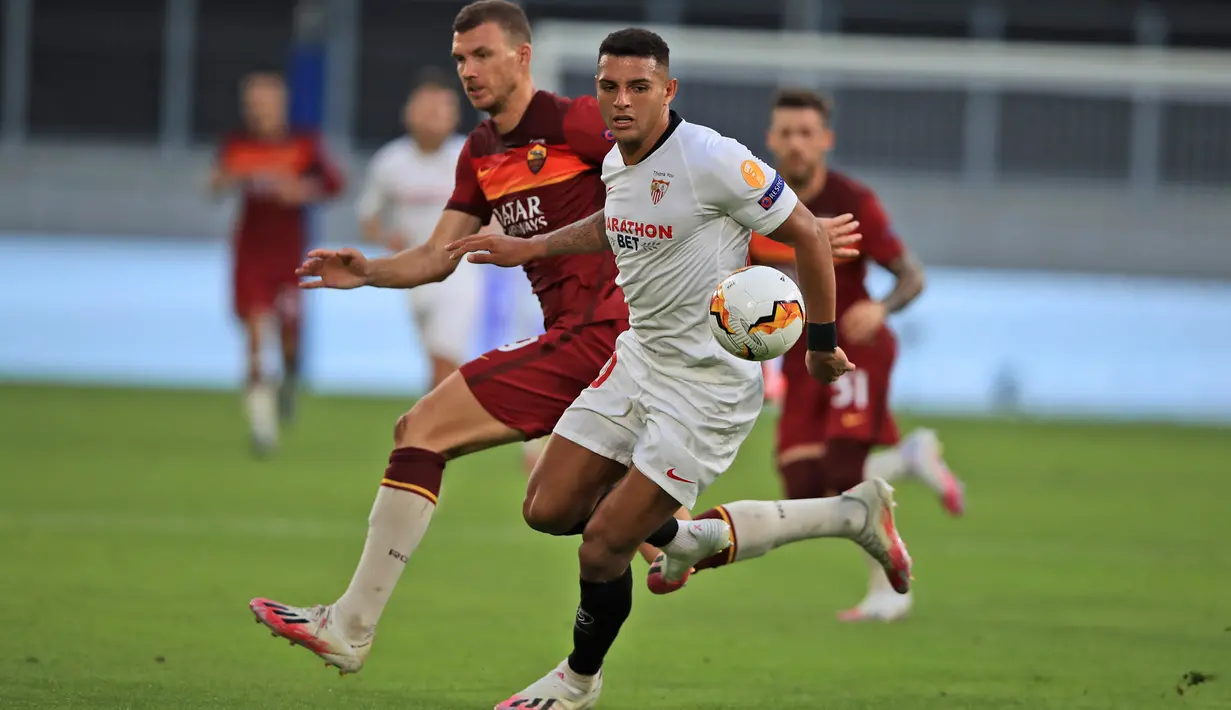 Bek Sevilla, Diego Carlos berebut bola dengan pemain AS Roma, Edin Dzeko pada babak 16 besar Liga Europa di Stadion Schauinsland-Reisen-Arena, Kamis (6/8/2020). Sevilla lolos ke perempat final setelah mengandaskan AS Roma dengan skor 2-0. (Wolfgang Rattay/Pool Photo via AP)