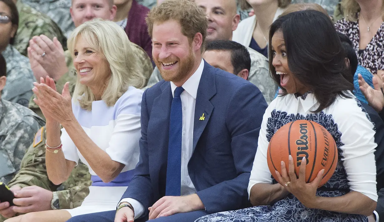 Michelle Obama menangkap bola saat menghadiri sebuah acara bersama Pangeran Harry di Fort Belvoir, Virginia, Rabu (28/10). Pertemuan ini diadakan untuk mendukung pelaksanaan Invictus Games Orlando kepada para tentara yang terluka. (AFP PHOTO/SAUL Loeb)