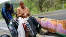 Migran Venezuela, Jefferson Alexis dan ayahnya, Jose Agustin Lopez beristirahat di tengah perjalanan menuju Bogota, Kolombia, 15 September 2018. Sepanjang perjalanan, Jefferson bersusah payah mendorong kursi roda sang ayah. (AFP/SCHNEYDER MENDOZA)