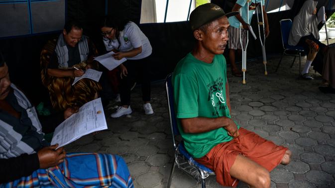 Seorang pria menunggu petugas melakukan pengukuran dan pencetakan kaki palsu di kantor Dinas Sosial Aceh, Senin (16/9/2019). Untuk tahun 2019 ini diberikan secara gratis sebanyak 100 kaki dan tangan palsu untuk para penyandang disabilitas di sejumlah kabupaten/kota. (CHAIDEER MAHYUDDIN / AFP)