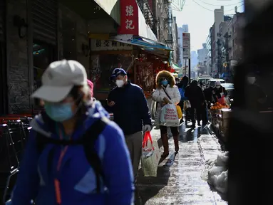 Orang-orang yang memakai masker berjalan di kawasan Chinatown di New York City pada 5 Februari 2021. Tahun Baru Imlek akan jatuh Jumat depan, 12 Februari, dan itu harusnya menjadi waktu tersibuk tahun ini untuk Chinatown, tetapi tidak pada tahun 2021 saat pandemi COVID-19 mewabah. (Angela Weiss/AFP)