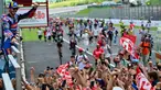 Pembalap Ducati Lenovo, Francesco Bagnaia melakukan selebrasi dengan para penggemarnya usai memenangi balapan MotoGP Italia di Mugello, 2 Juni 2024. (Marco BERTORELLO/AFP)