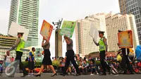 Anggota Polisi berjalan sambil membawa poster saat parade busana POLRI di car free day di Bunderan HI, Jakarta (5/2). (Liputan6.com/Angga Yuniar)