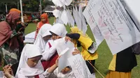 Para siswa-siswi SD SLBN A Kota Bandung membaca kertas braille berisi harapan terhadap sekolahnya pada acara peringatan Hari Disabilitas Internasional, Jumat (6/12/2019). (Liputan6.com/Huyogo Simbolon)