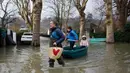 Seorang wanita menggunakan perahu membawa anak-anak di sebuah jalan banjir di Villennes sur Seine, sebelah barat Paris, (30/1). Sejumlah perjalanan kapal pesiar juga tergangu akibat hujan deras yang membuat sungai meluap. (AP Photo / Thibault Camus)