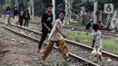 Anak-anak melintas di tengah perlintasan kereta api kawasan Ancol, Jakarta Utara, Kamis (19/5/2022). Dari 14 kasus dugaan hepatitis akut terdapat 6 kasus meninggal dunia, 4 kasus masih dirawat, dan 4 kasus sudah dipulangkan. (Liputan6.com/Johan Tallo)