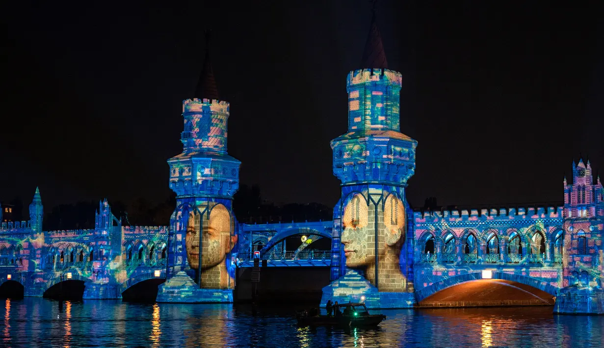 Cahaya warna-warni diproyeksikan pada fasad jembatan Oberbaumbruecke di atas sungai Spree sebagai bagian dari Festival of Lights di Berlin, 15 September 2020. Kreasi cahaya lebih dari 90 karya seni tersebut ditampilkan di 86 lokasi yang berlangsung hingga 20 September mendatang (John MACDOUGALL/AFP)