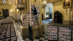 Pekerja menempelkan potret korban meninggal akibat virus corona di dalam Katedral, di Lima, Peru pada 13 Juni 2020. Misa Minggu di Katedral Lima dihadiri lebih dari 4.000 potret mereka yang telah meninggal dalam pandemi Covid-19 yang menyebar di Peru. (AP Photo/Rodrigo Abd)