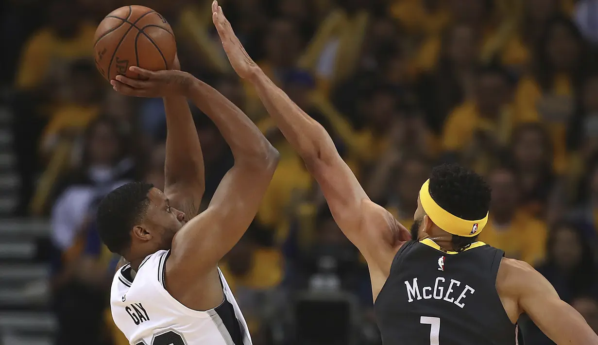 Aksi pemain San Antonio Spurs, Rudy Gay (kiri) melepaskan tembakan melewati adangan pemain Golden State Warriors, JaVale McGee pada playoffs NBA Basketball di Oracle Arena, Oakland, California, (16/4/2018). Warriors menang 116-101. (AP/Ben Margot)