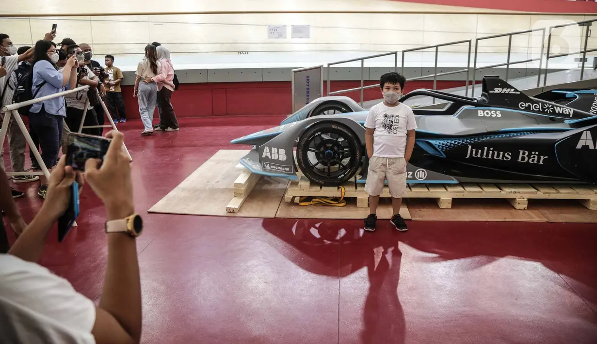Seorang anak berfoto di depan replika mobil Formula E setelah dibuka untuk kali pertama di Stadion Balap Sepeda Velodrome, Rawamangun, Jakarta Timur, pada Kamis (26/5/2022). Ini merupakan replika salah satu mobil Formula E yang akan mengaspal di Sirkuit Ancol pada 4 Juni mendatang. (Liputan6.com/Faizal Fanani)