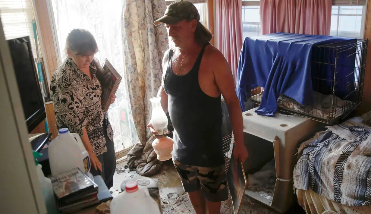 Barbara Sizemore dan Junior Stricker menyelamatkan beberapa barang di rumah setelah bencana banjir di Clendenin, Virginia Barat, Minggu (26/6). West Virginia mendapat seperempat dari curah hujan tahunannya hanya dalam sehari. (REUTERS/Marcus Constantino)