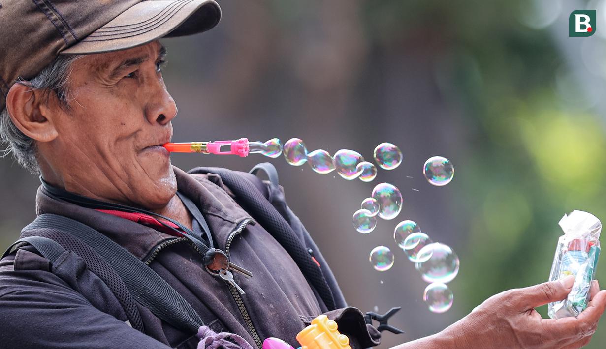 Seorang penjual mainan gelembung sedang menjajakan dagangannya di Taman Bungkul yang terletak di Jalan Raya Darmo, Wonokromo, Surabaya, Selasa (14/11/2023). (Bola.com/Bagaskara Lazuardi)