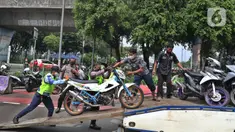 Petugas mengangkut motor berknalpot bising saat razia di kawasan Monas, Jakarta, Minggu (7/3/2021). Direktorat Lalu Lintas Polda Metro Jaya mengeluarkan kebijakan larangan kendaraan bermotor berknalpot bising melintas di kawasan Monas pada hari Sabtu dan Minggu. (Liputan6.com/Herman Zakharia)