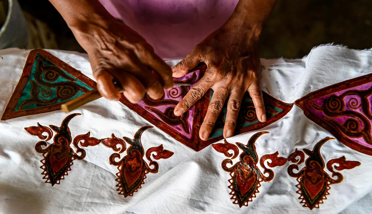 Seorang pekerja membuat desain batik di sebuah bengkel di Banda Aceh, Aceh, Rabu (13/10/2021). Batik Aceh memiliki ciri khas tersendiri, yaitu menggunakan perpaduan unsur alam dan budaya dari masyarakat Aceh sendiri. (Chaideer MAHYUDDIN/AFP)