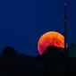 Bulan tampak berwarna merah darah saat terjadinya fenomena gerhana bulan total  di Luzern, Swiss, Jumat (27/7). Gerhana bulan yang terlama pada abad ini dapat disaksikan di seluruh dunia dengan mata telanjang. (Christian Merz/Keystone via AP)