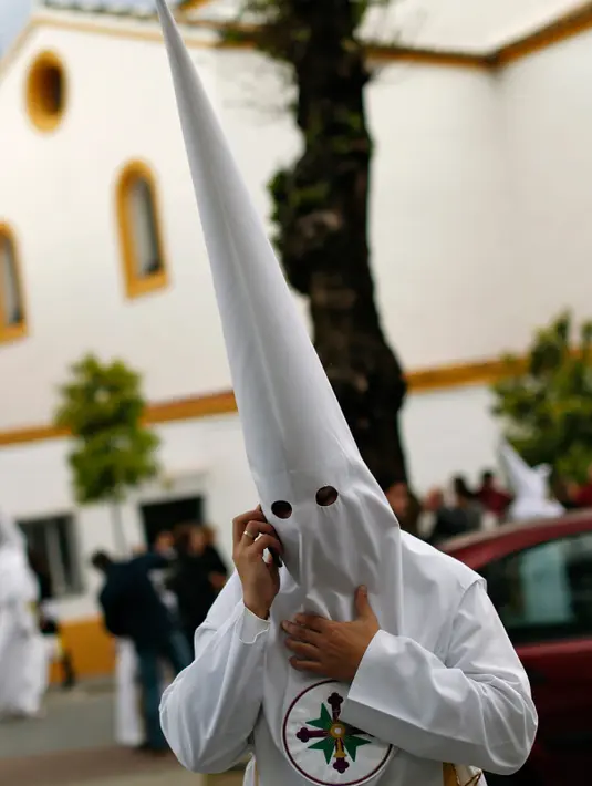Orang berpakain capirote sedang memegang handphone saat mengikuti prosesi Pekan Suci di ibukota Andalusia, Spanyol, (21/3). Capirote merupakan merupakan perwujudan rasa penyesalan dan pertobatan dari yang mengenakannya. (REUTERS / Marcelo del Pozo)