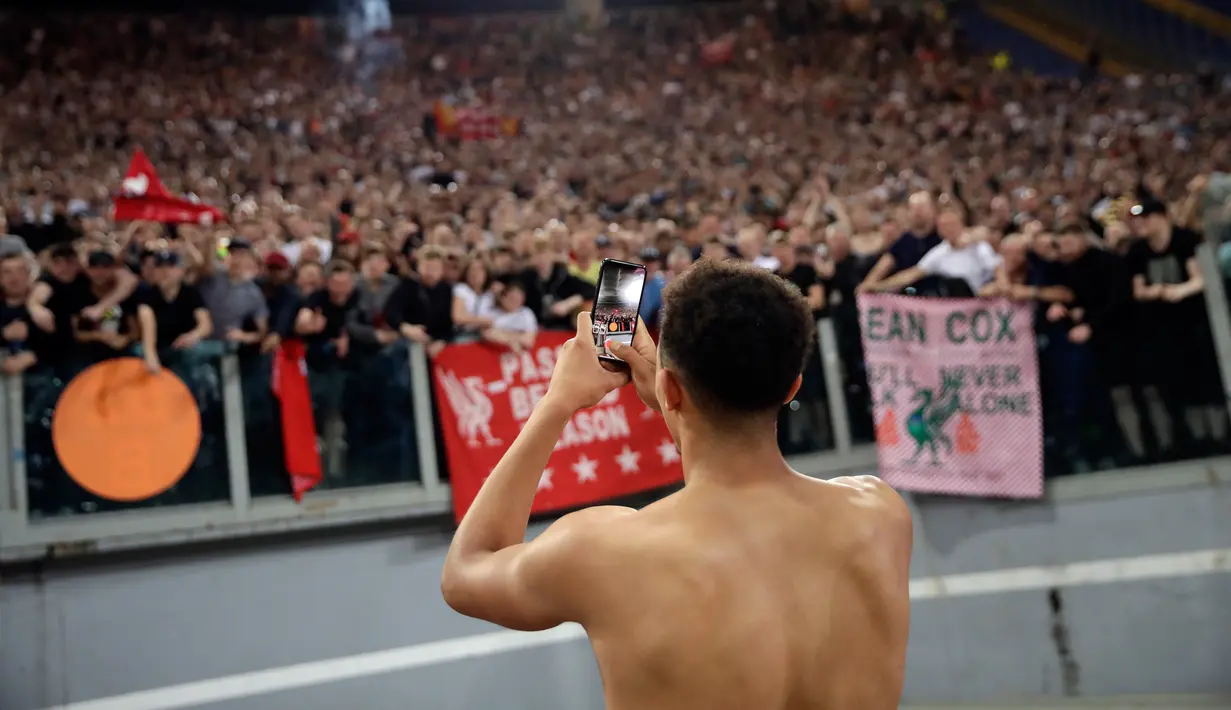 Bek Trent Alexander-Arnold mengambil foto para pendukung Liverpool saat merayakan lolos ke final Liga Champions di Stadion Olimpiade di Roma (2/5). Liverpool melaju ke final usai menang agregat 7-6 atas Roma. (AP Photo/Alessandra Tarantino)