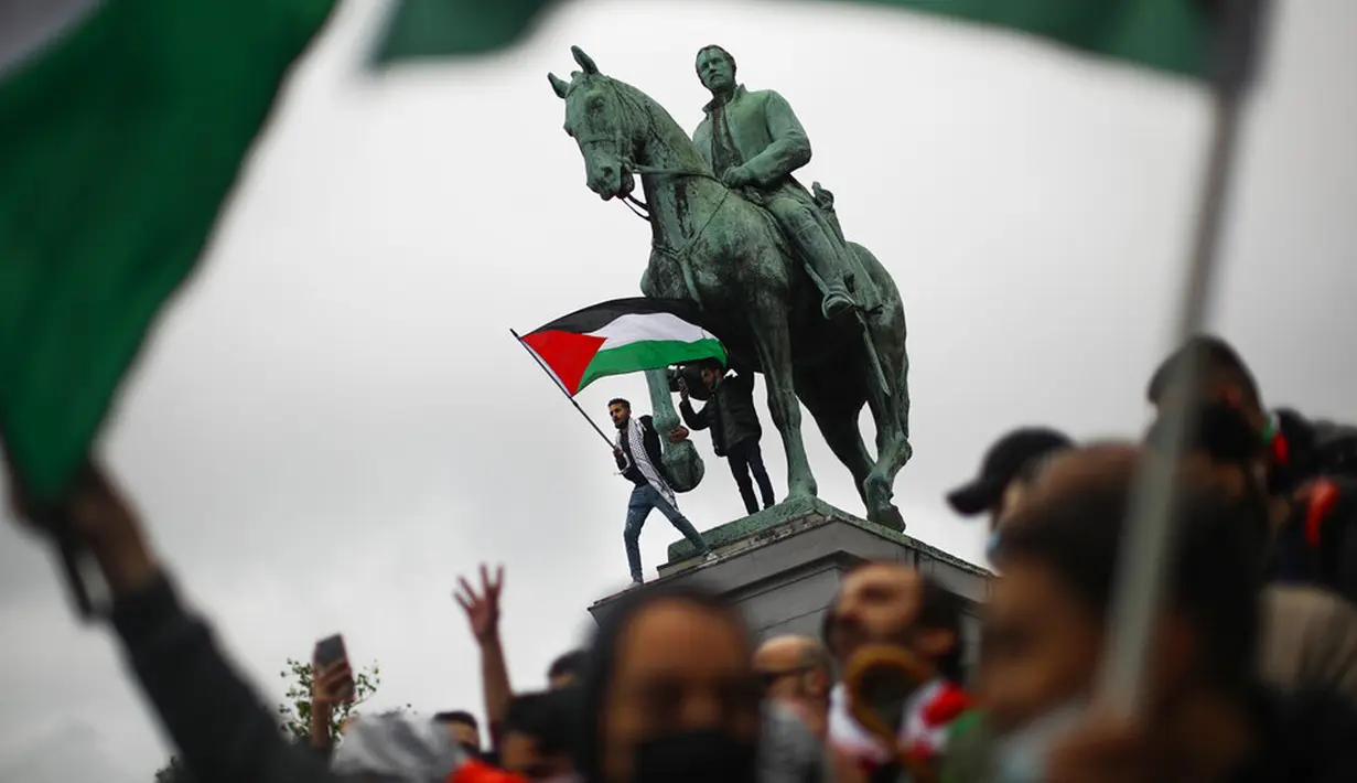 Seorang pria mengibarkan bendera Palestina sambil meneriakkan slogan-slogan dengan orang lain selama protes untuk mendukung warga Palestina di Jalur Gaza di Brussel, Belgia, Sabtu (15/5/2021). (AP Photo/Francisco Seco)