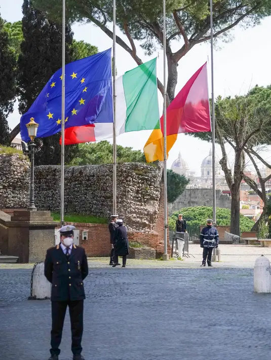 Bendera nasional Italia dikibarkan setengah tiang saat mengheningkan cipta selama satu menit di Capitol Hill Roma, Selasa (31/3/2020). Italia mengheningkan cipta dan menaikkan bendera setengah tiang untuk memberikan penghormatan bagi para korban virus corona dan keluarga mereka (AP/Andrew Medichini)