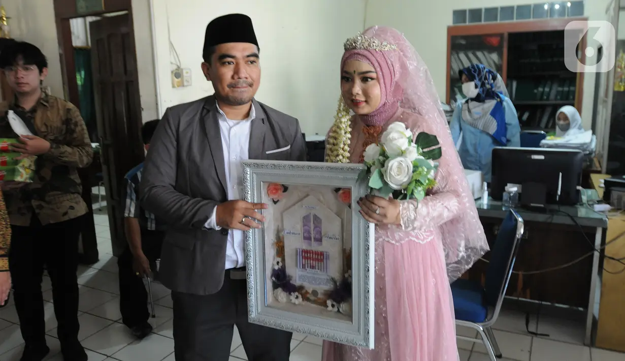 Sepasang pengantin yang menikah pada tanggal cantik hari ini di KUA Pamulang, Tangerang Selatan, Selasa (22/2/2022). Sebanyak 10 pasangan menjalankan akad nikah di KUA Pamulang pada hari ini yang dianggap memiliki tanggal cantik. (merdeka.com/Arie Basuki)