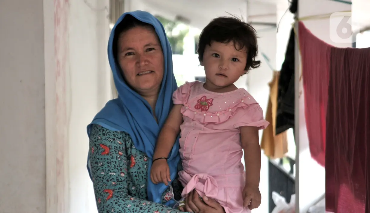 Seorang imigran pencari suaka menggendong anak di penampungan sementara di Kalideres, Jakarta, Rabu (18/12/2019). Untuk listrik, para imigran di tempat ini secara swadaya atau patungan membayar tagihan. (merdeka.com/Iqbal Nugroho)