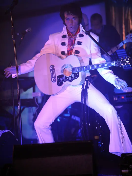 Penampilan peniru gaya Elvis Presley, Pete Storm dari Inggris saat Festival Elvis Skotlandia yang digelar pertama kali di Grangemouth, 8 April 2016. Acara ini memikat penonton yang ingin menyaksikan aksi kontestan mirip Elvis Presley. (Andy Buchanan/AFP)