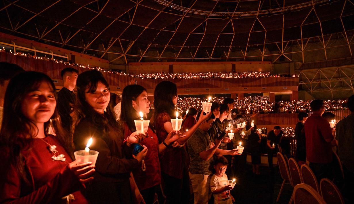 Umat Kristiani menyalakan lilin selama misa Hari Natal di Gereja Bethany, Surabaya, Jawa Timur pada Kamis 25 Desember 2025. (JUNI KRISWANTO/AFP)