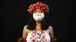 Yusuro Dupohtiro (15) dari kelompok etnis pribumi Dessana dan Sateré Mawé mengenakan pakaian tradisional sukunya dan masker saat pandemi virus corona COVID-19 di Manaus, Brasil, Rabu (27/5/2020). (AP Photo/Felipe Dana)