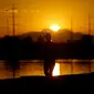 Seorang pelari jogging di sepanjang Danau Kota Tempe saat matahari terbit, Rabu, 12 Juli 2023 di Tempe, Arizona. Jutaan orang di seluruh Barat Daya mengalami gelombang panas bersejarah. (AP Photo/Matt York)