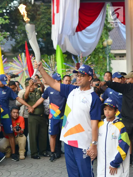 Gubernur DKI Jakarta, Anies Baswedan bersama putranya membawa Api Obor Asian Games 2018 setelah mengelilingi dari Jakarta Timur dan Jakarta Selatan di Balai Kota, Jakarta, Rabu (15/8). (Liputan6.com/Fery Pradolo)