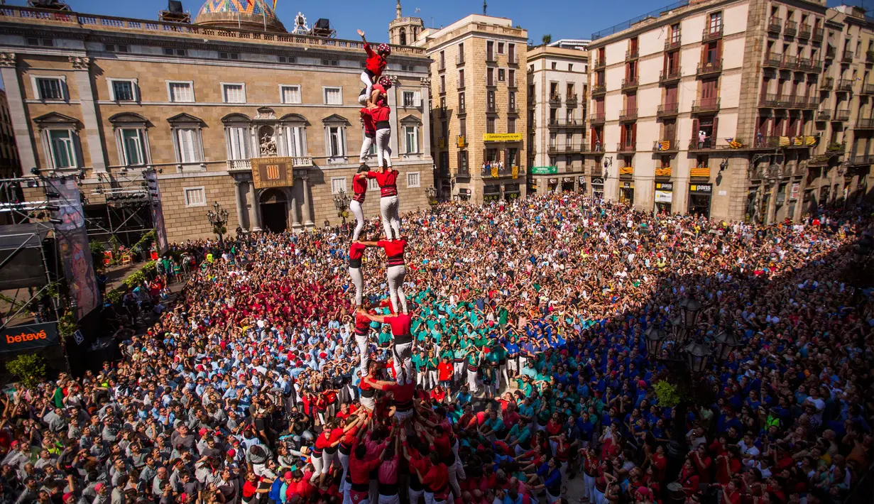 Anggota ‘Castellers’ Barcelona membentuk menara manusia yang disebut ‘Castell’ di alun-alun Sant Jaume, Barcelona, Spanyol, Minggu (24/9). Kelompok akar rumput memimpin gerakan kemerdekaan Catalonia dengan membangun Castell. (AP Photo/Emilio Morenatti)