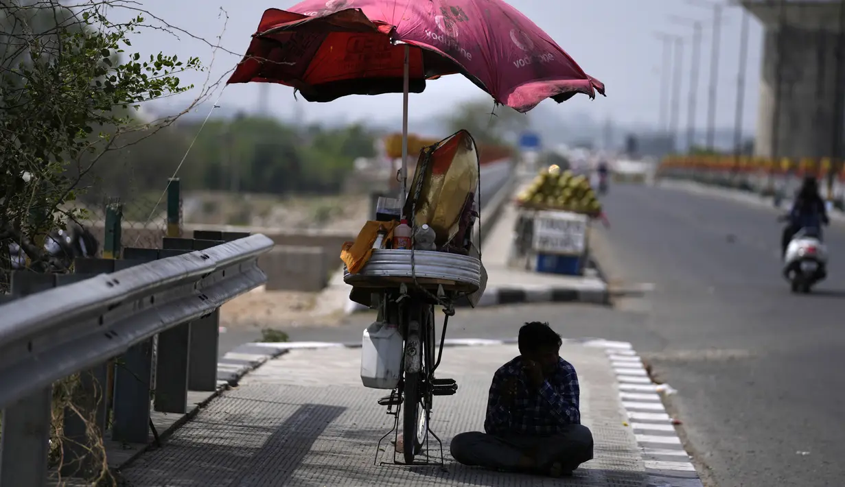 <p>Seorang penjual makanan ringan duduk di bawah naungan dan menunggu pelanggan pada sore musim panas yang terik di Jammu, India, Kamis (19/5/2022). Banyak bagian barat laut dan tengah India terus mengalami kondisi gelombang panas. (AP Photo/Channi Anand)</p>