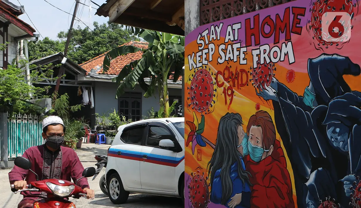 Pemotor melintas di depan mural bertema virus corona COVID-19 yang menghiasi dinding rumah di kawasan Pangkalan Jati Baru, Depok, Jawa Barat, Selasa (2/6/2020). Mural bertulis ‘Stay At Home, Keep Safe From COVID-19’ itu untuk mengingatkan warga akan bahaya COVID-19. (Liputan6.com/Johan Tallo)