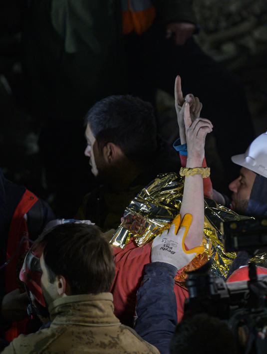 Seher, seorang wanita Suriah berusia 15 tahun mengangkat tangannya saat dia dibawa dengan tandu oleh petugas penyelamat setelah diselamatkan dari bawah reruntuhan tempat dia terjebak di Hatay, tenggara Turki, pada 14 Februari 2023. Lebih dari 35.000 orang tewas di Turki akibat gempa minggu lalu, menjadikannya bencana paling mematikan sejak negara itu didirikan 100 tahun lalu. (AFP/Yasin AKGUL)