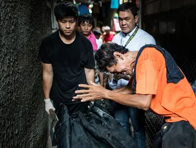 Gambar yang diambil pada 1 September 2016 menunjukkan kesedihan seorang ayah dari pengguna narkoba saat petugas mengevakuasi jasad anaknya yang diduga tewas dibunuh oleh polisi di Manila, Filipina. (AFP PHOTO/Noel CELIS)