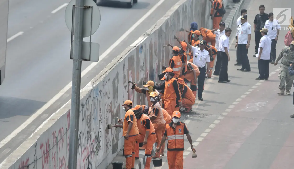 Petugas PPSU membersihkan coretan yang mengotori tembok di kawasan Gedung DPR, Jakarta, Rabu (25/9/2019). Demonstrasi mahasiswa yang berujung ricuh yang berujung kerusuhan tersebut menyebabkan fasilitas umum rusak dan penuh coretan yang dibuat oleh pendemo. (merdeka.com/Iqbal S Nugroho)