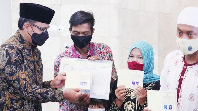 Buku nikah, kartu keluarga (KK), e-KTP dan Akta Kelahiran diserahkan secara simbolis oleh Wali Kota Bogor, Bima Arya kepada 43 pasangan yang baru saja melangsungkan pernikahan massal, Sabtu (11/12/2021). (Liputan6.com/Achmad Sudarno)