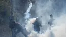 Demonstran melempar kembali gas air mata ke arah polisi di La Paz, Bolivia, Selasa (21/2). Demonstran protes kebijakan baru Presiden Evo Morales terkait petani daun koka. (AP Photo / Juan Karita)