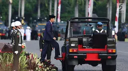 Presiden Joko Widodo (Jokowi) menaiki mobil komando untuk melakukan pemeriksaan pasukan Polri pada peringatan HUT ke-71 Bhayangkara di Monas, Jakarta, Senin (10/7). Jokowi menjadi instruktur upacara dalam acara tersebut. (Liputan6.com/Angga Yuniar)