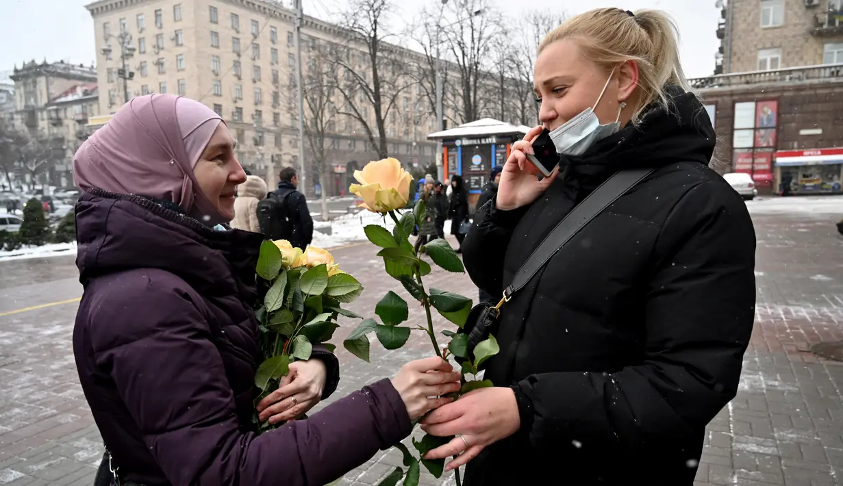 Seorang aktivis dari Asosiasi Perempuan Muslim Ukraina memberikan bunga kepada pejalan kaki selama perayaan World Hijab Day di Kiev, Senin (1/2/2021). Hari Hijab Sedunia untuk menunjukkan solidaritas dengan wanita Muslim yang mengalami diskriminasi untuk mengenakan hijab. (Sergei SUPINSKY/AFP)