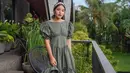 Dalam foto ini, Tiffany Soetanto berpose dalam balutan princess midi-dress berwarna hijau muda, dengan detail kerut dan lengan balon yang pendek dari brand Miroir Store. Ia padu dengan bando cokelat dan sandal kasual yang manis. Foto: Instagram.