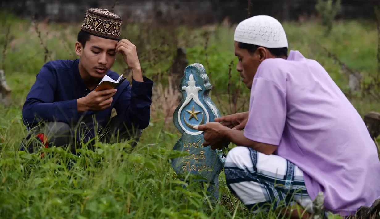 Seorang pria memanjatkan doa di makam kerabatnya saat Idul Fitri di Provinsi Narathiwat, Thailand, Rabu (5/6/2019). Tradisi ziarah kubur saat Idul Fitri ini mirip dengan apa yang biasa dilakukan muslim di Indonesia. (MADAREE TOHLALA/AFP)
