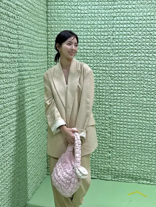Chae Soo Bin mengenakan setelan warna beige, memadukan blazer oversize dengan celana panjang. Ia membawa tas cloudy warna pink. [@soobinms]