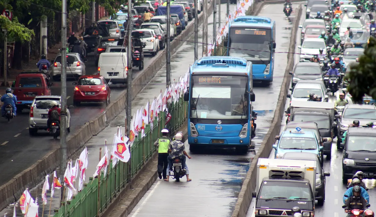 Petugas kepolisian lalu lintas merazia pengendara sepeda motor yang melintasi jalur bus Transjakarta di Jalan Sultan Agung, Manggarai, Jakarta, Kamis (6/2/2020). Meski melanggar, sebagian pengguna jalan secara sengaja masuk dan menggunakan jalur khusus bus tersebut. (Liputan6.com/Helmi Fithriansyah)
